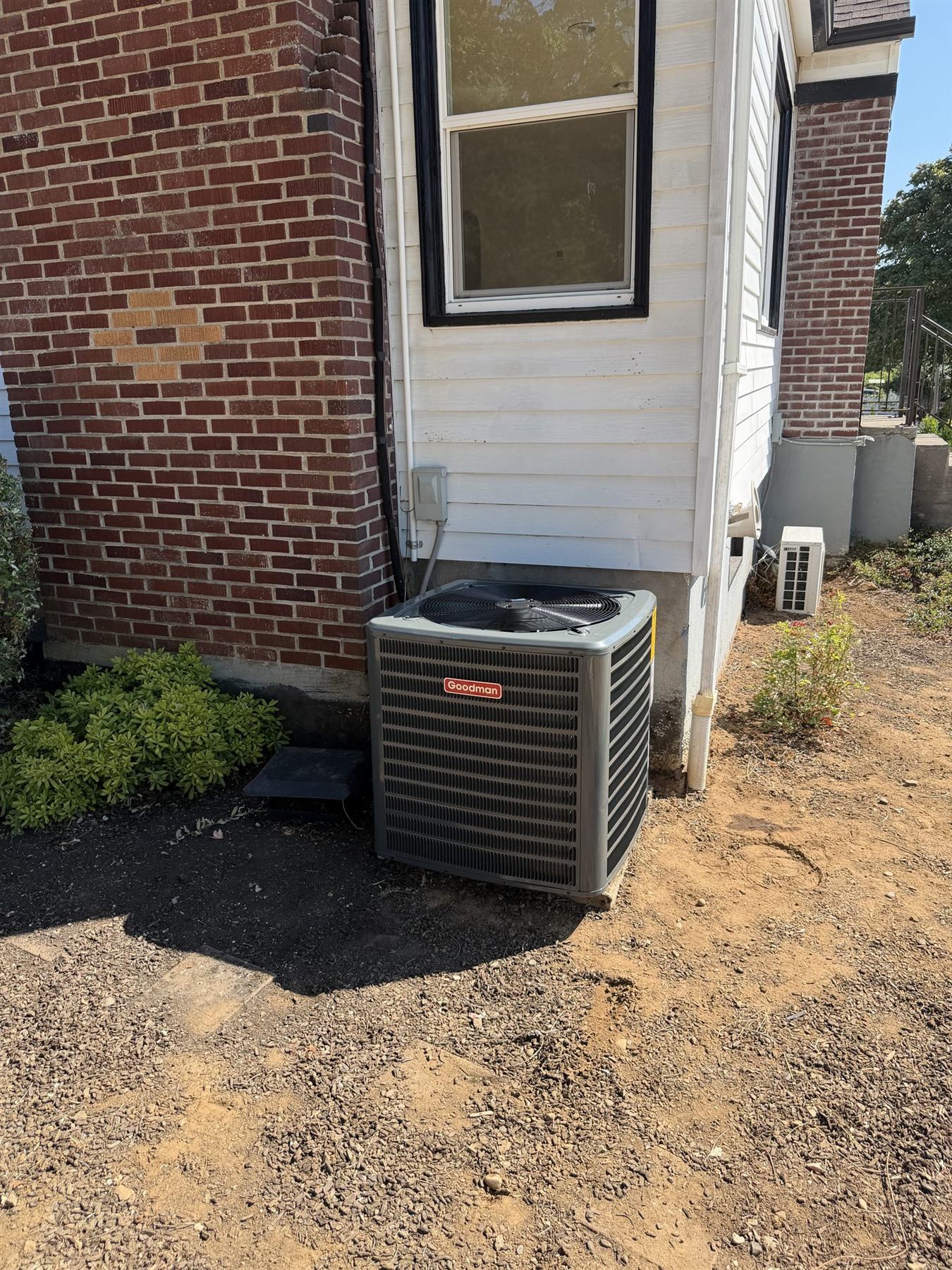 A Goodman outdoor unit beside a brick house